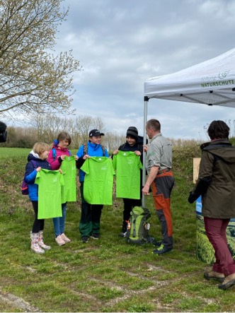 Vier Kinder halten jeweils ein grünes T-Shirt hoch.