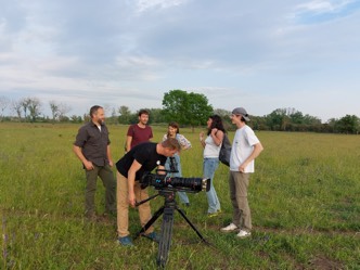 Sechs Personen stehen um eine Kamera mit großem Objektiv