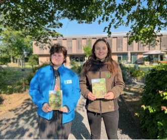 Zwei junge Personen halten die „Forscherheft“ „Wald, Wiese und du“ in der Hand.